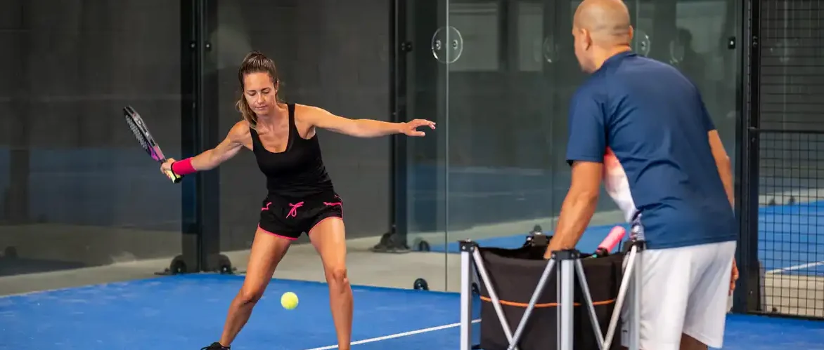 afbeelding van een vrouw die padel les krijgt